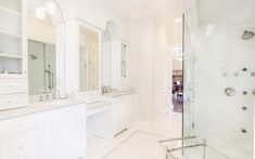 a large bathroom with white cabinets and marble counter tops, along with a walk in shower