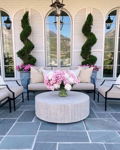 an outdoor living area with couches, tables and flowers