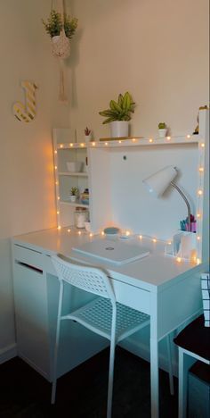 a white desk topped with a laptop computer next to a window covered in fairy lights