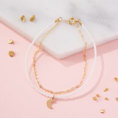 A delicate layered friendship bracelet featuring gold plated chain, teeny tiny beads in white or black and a gold moon charm at the centre. This minimalist but intricate gold chain bracelet is hand-threaded with miniscule glass beads and a gold plated crescent-moon charm. Hanging alongside the tiny beaded bracelet is a dainty gold plated chain, all fixed under the one clasp. The layered look made easy! This simple monochrome bracelet comes in a choice of white beads or black beads. ALSO AVAILABL Dainty White Beaded Bracelets With Adjustable Chain, Minimalist White 14k Gold Filled Beaded Bracelets, White 14k Gold Filled Bracelets With Adjustable Chain, White Dainty Jewelry With Moon Charm, Adjustable White 14k Gold-filled Bracelets, Adjustable White 14k Gold-filled Bracelet, Everyday White Jewelry With Moon Charm, Everyday White Moon Charm Jewelry, Minimalist White Bracelet With Delicate Chain