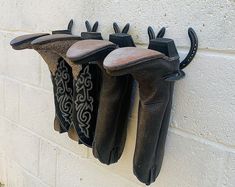 three pairs of black leather gloves hanging on a white brick wall next to each other