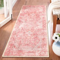 a large red rug on the floor in a room with wooden floors and white walls