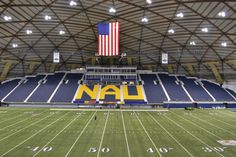 an empty football stadium with the american flag hanging from the ceiling and lights on the sidelines