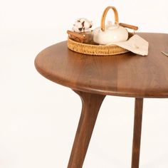 a wooden table topped with a basket and a white teapot on top of it