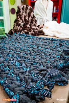 there is a large blue and black blanket on the table in front of a bed