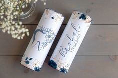 two personalized tumbles sitting on top of a wooden table next to a vase with flowers