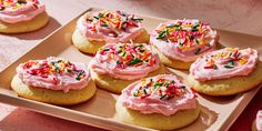 there are many cookies with pink frosting and sprinkles on them sitting on a plate