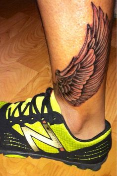 a person's foot with a tattoo on it and an angel wing above the shoe