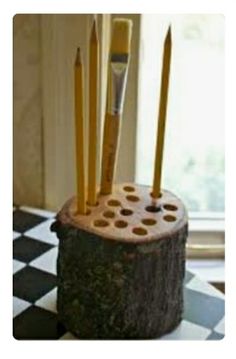 a wooden holder with pencils and brushes in it on a checkered tablecloth