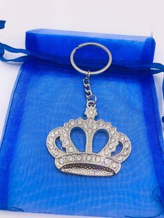 a key chain with a crown on it sitting in a blue bag next to a ribbon