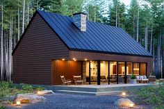 a small cabin in the woods with lights on it's front porch and patio