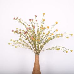 a vase filled with yellow flowers on top of a wooden table next to a white wall