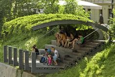 several people are sitting on the stairs in front of some trees and bushes, while one person is taking pictures