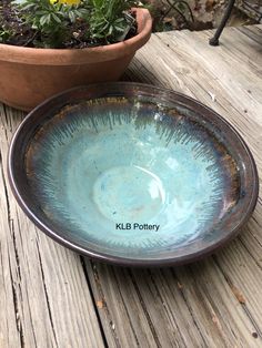 a bowl sitting on top of a wooden table next to a potted plant