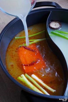 a pot filled with soup and vegetables being poured into it