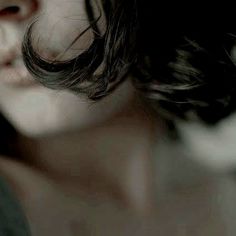 a close up of a woman's face with her hair blowing in the wind