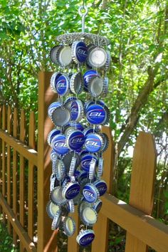 a wind chime made out of beer cans hanging from a wooden fence