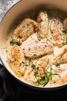 a pan filled with chicken and gravy on top of a table next to a black cloth