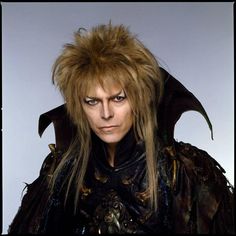 a man with long hair and demon makeup looks at the camera while wearing a costume