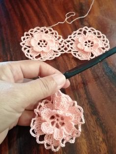 someone is crocheting some pink flowers on a table