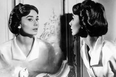 an old black and white photo of two women looking at each other in the mirror