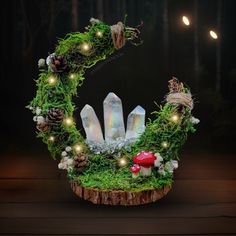 a wreath made out of moss and rocks with fairy lights in the middle on a wooden table