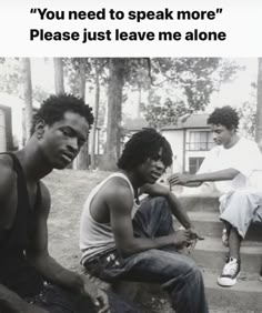 three young men sitting on steps in front of trees and one is holding a cell phone