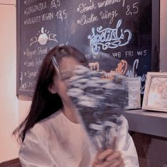 a woman sitting in front of a blackboard with writing on it