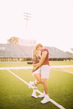 a man and woman standing on top of a football field