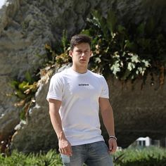 a young man standing in front of a rock formation with his hands in his pockets