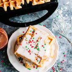 waffles with white icing and sprinkles are on a plate