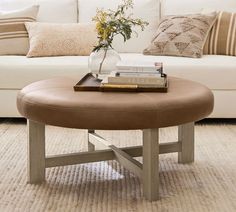 a living room with a white couch, coffee table and books on top of it