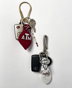 two keychains with tags attached to them on a white surface, one has an atm tag and the other has a mickey mouse