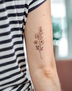 a woman's arm with a small flower tattoo on the left side of her arm