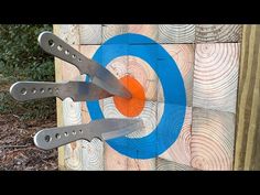 there are three knives stuck in the center of an archery target that is blue and orange