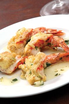 a white plate topped with shrimp next to a glass of wine