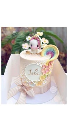 there is a small cake decorated with flowers and a unicorn on it's side