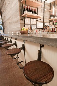 an empty bar with stools and bottles on the shelves