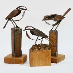 three metal birds sitting on top of wooden blocks