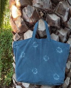 a blue tote bag sitting on top of a pile of wood next to a tree