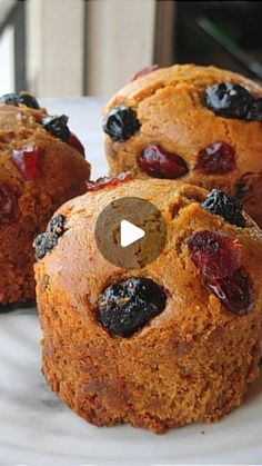 three muffins on a plate with raisins and cranberry topping