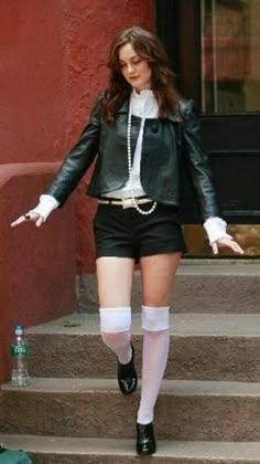 a woman in short black shorts and white socks walking down stairs with her arms outstretched