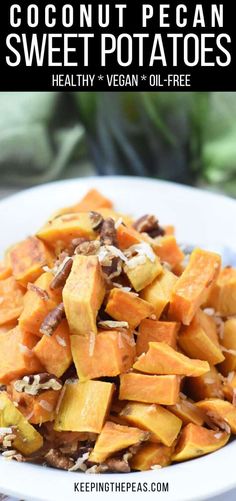 a white plate filled with sweet potatoes and nuts on top of a table next to a plant