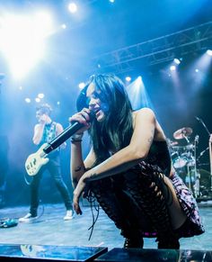 a woman sitting on top of a stage while holding a microphone