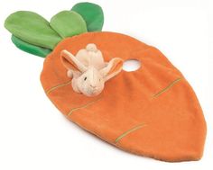 a stuffed animal carrot on top of a green leaf shaped object with leaves attached to it