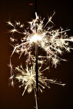 a close up of a dandelion with lots of sparklers in the air