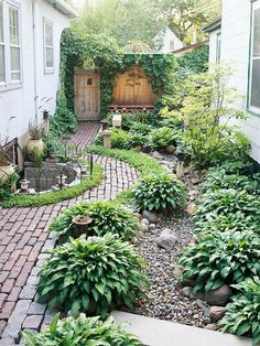 a small garden with lots of plants and rocks in it, along with a brick walkway