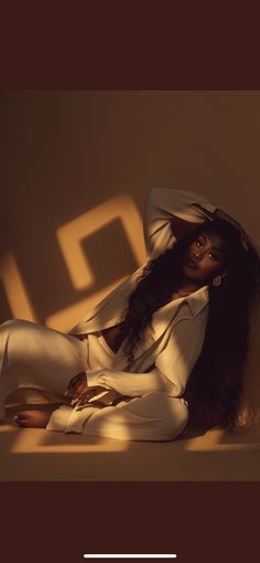 a woman sitting on the ground with her legs crossed and wearing white clothing, posing for a photo