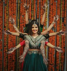 a woman in a green and red outfit with her arms spread out, surrounded by orange flowers