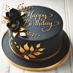 a black and gold birthday cake sitting on top of a white wooden table with the words happy birthday written on it